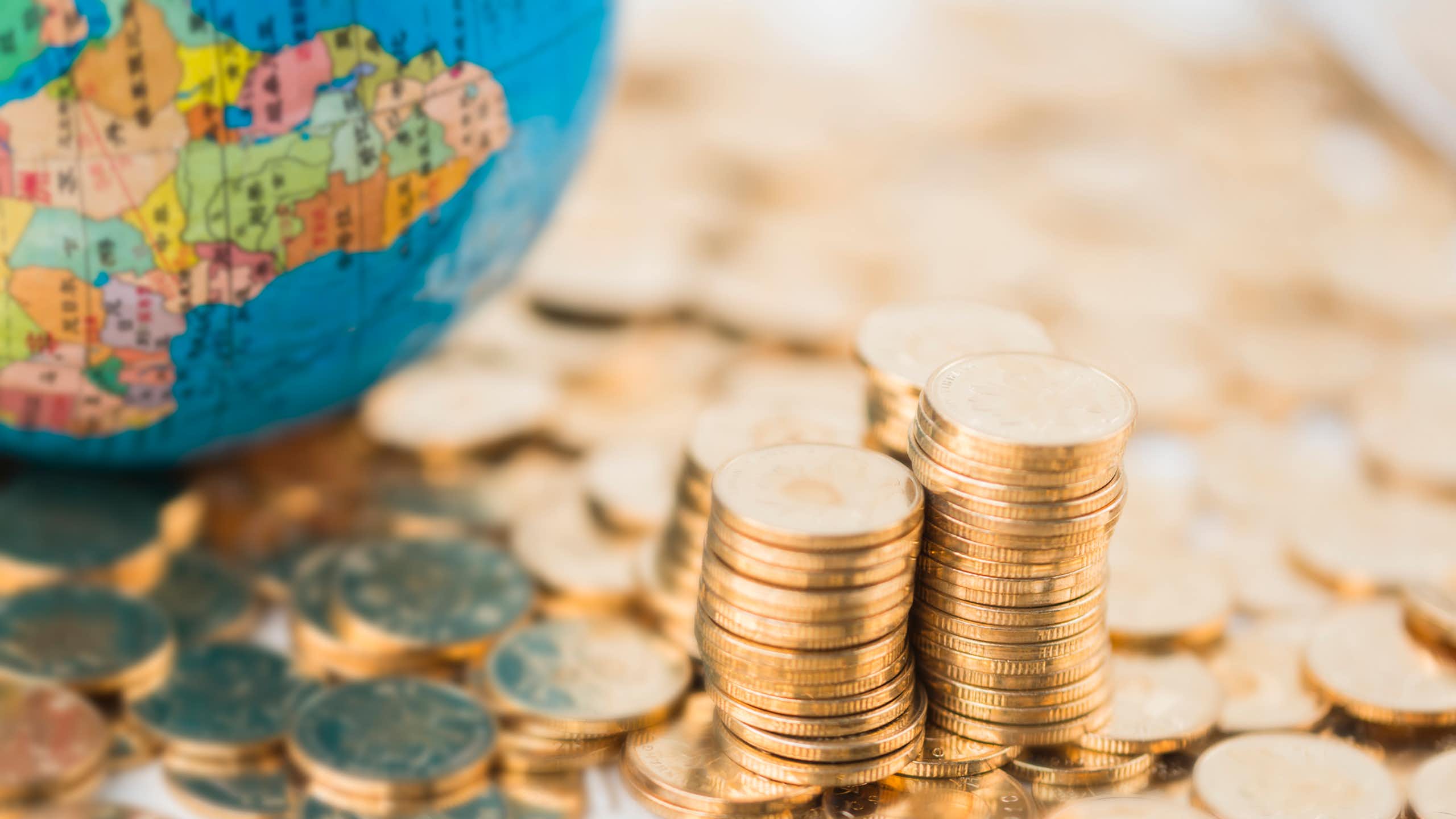 Coins scattered and piled next to a globe with map of Africa on it