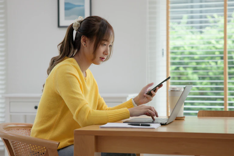 Girl using laptop and phone