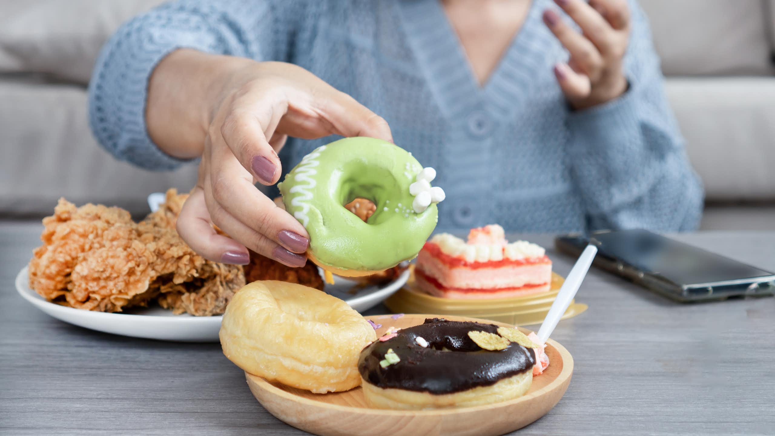 woman sitting at a table with colorful pastries and fried food.