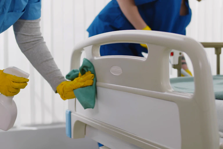 People cleaning a hospital bed.