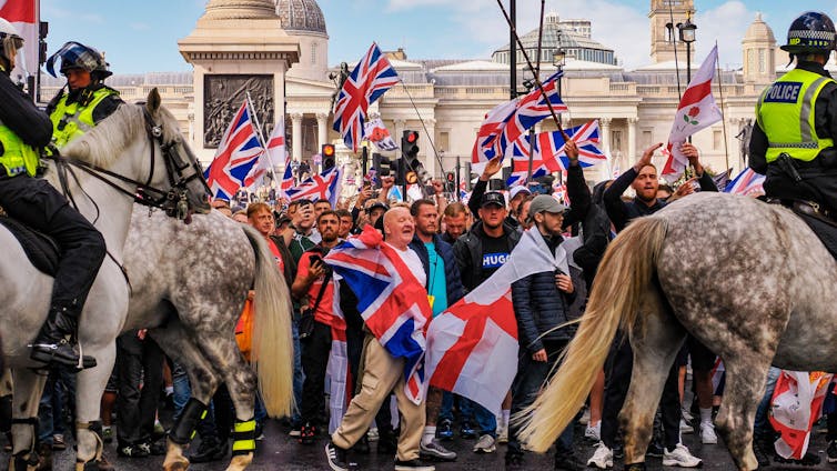 PRotesters waving flags as mounted police go by.