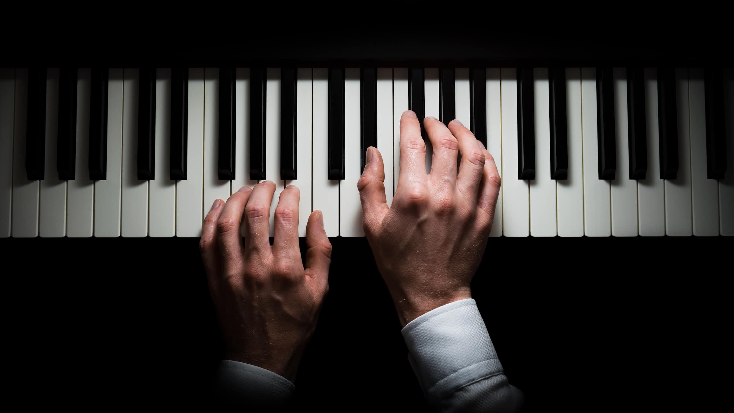 Hands on a piano keyboard.