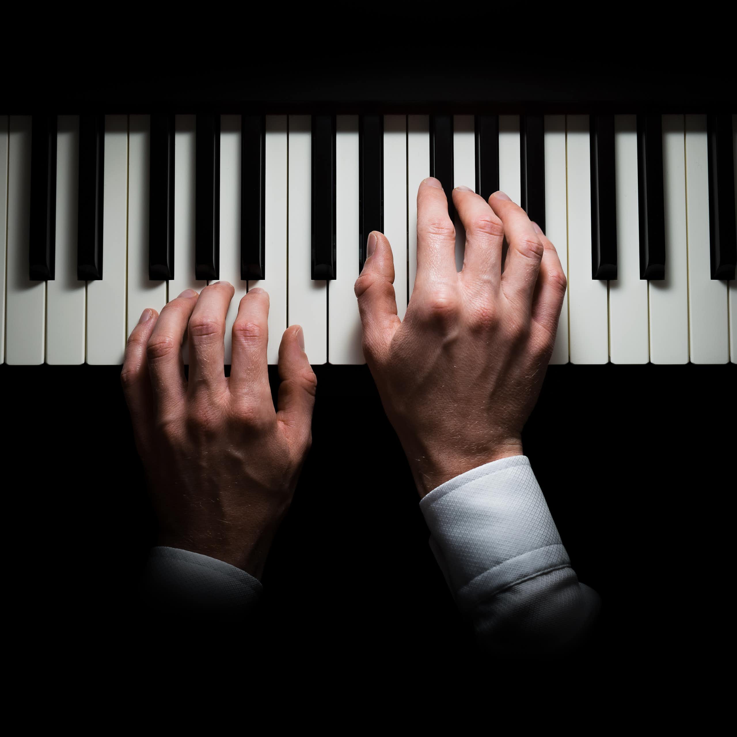 Hands on a piano keyboard.