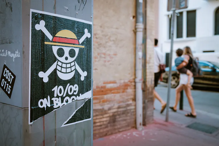 People walk past a skull-and-crossbones poster.