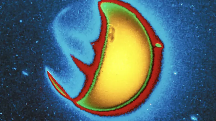 A radarlike image of a sphere, with a bright spot shown in yellow, with a green and red outline.