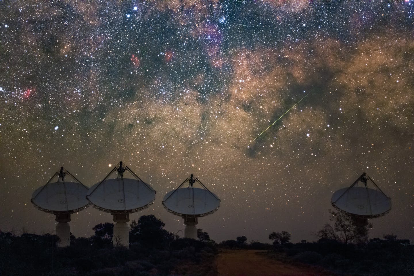 Radio telescope dishes beneath an intense starry sky