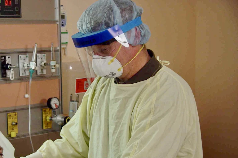 Man wearing a white respirator mask with a patient.