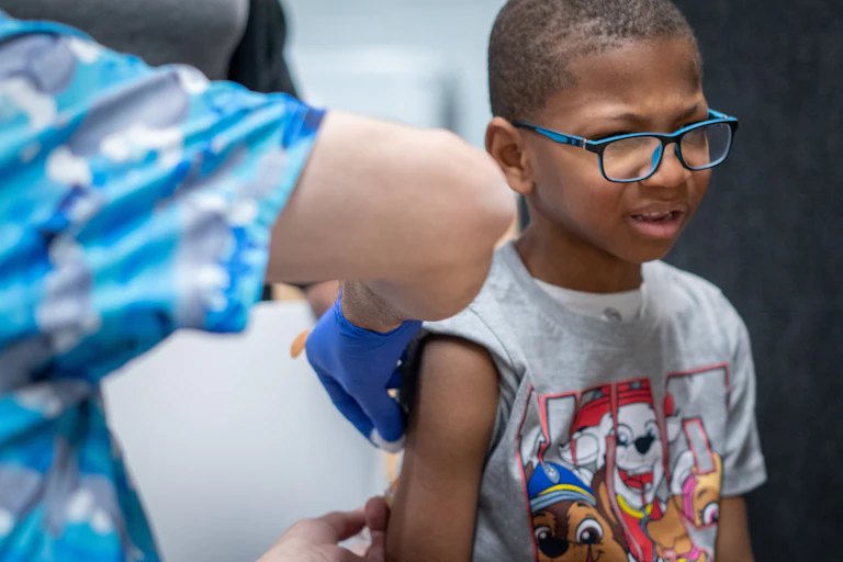 A young boy with a pained look on his face gets a vaccination.
