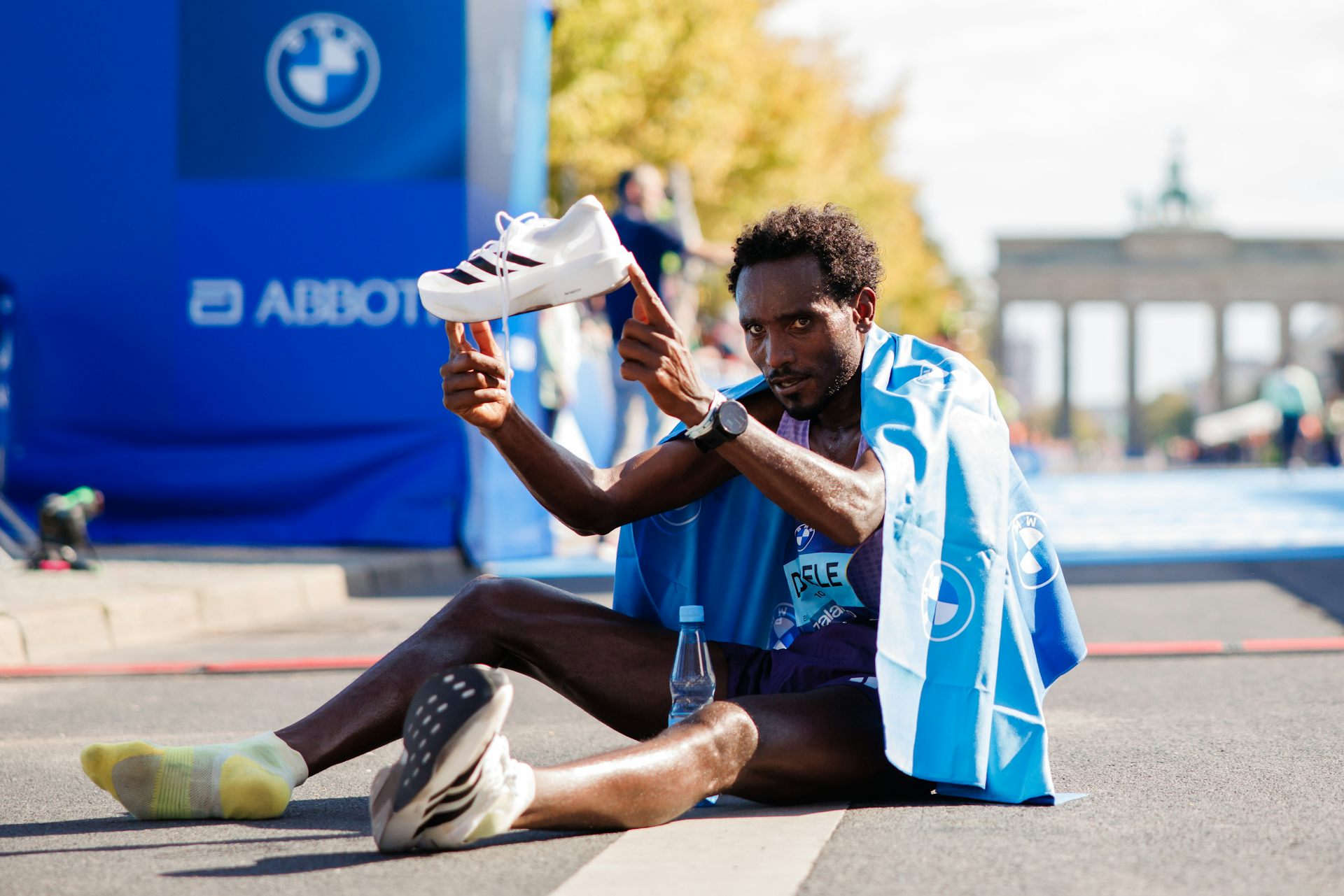 Chimdessa Debele of Ethiopia poses with his shoe after coming third in the 2025 Berlin Marathon.