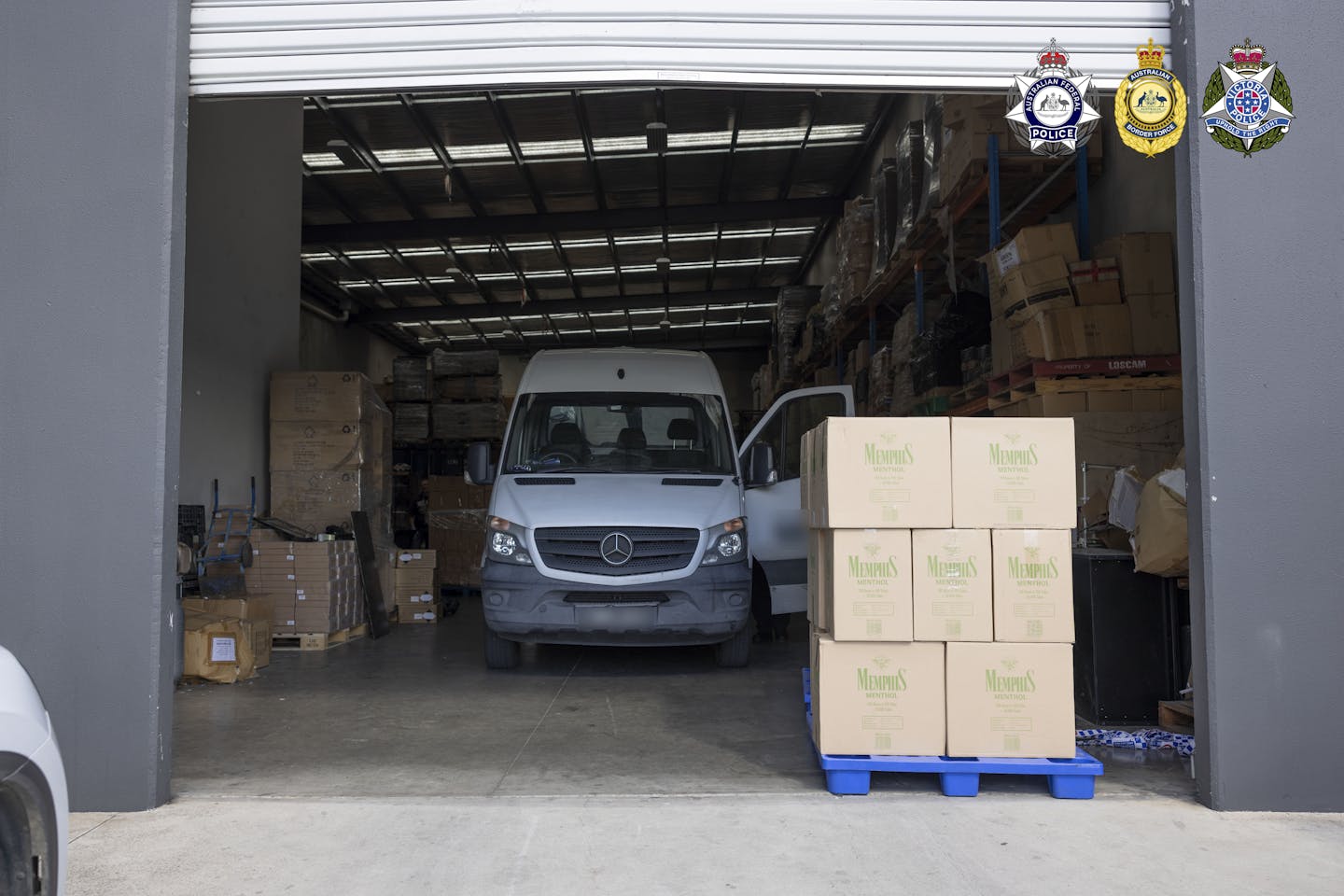 A stacked pallet of tobacco product boxes outside a raided warehouse.