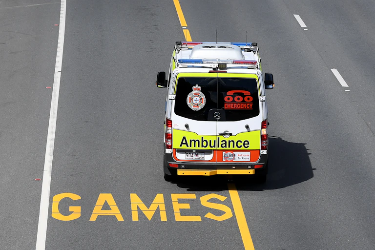 A red and white ambulance driving along an empty road.