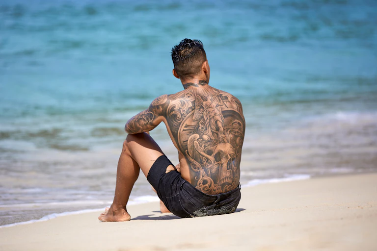 Tattooed man on the beach.
