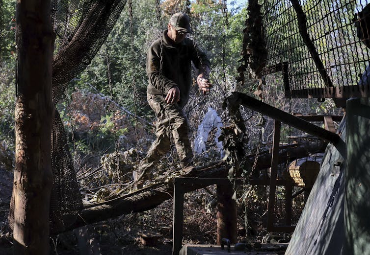 A member of the Ukrainian armed forces inspecting anti-drone protections.