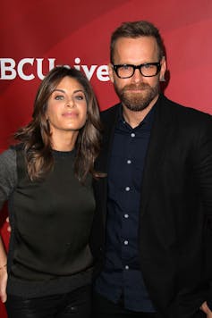 An smiling white man and woman standing together for the cameras.