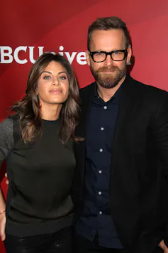 An smiling white man and woman standing together for the cameras.