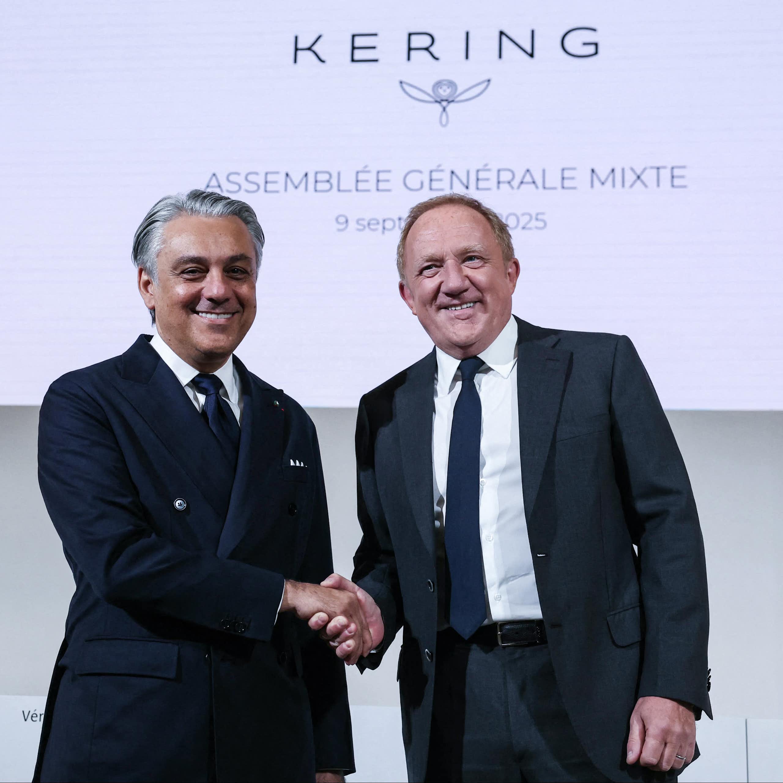 A handshake between Luca de Meo (left) and François-Henri Pinault (right) in front of a Kering logo.