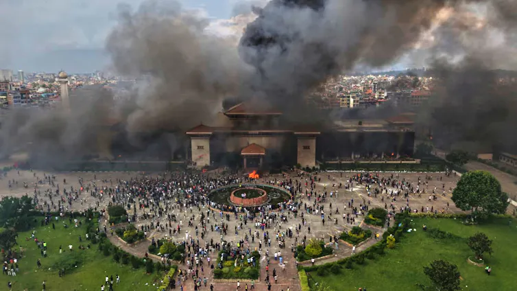 Hundreds of people outside a burning parliament building