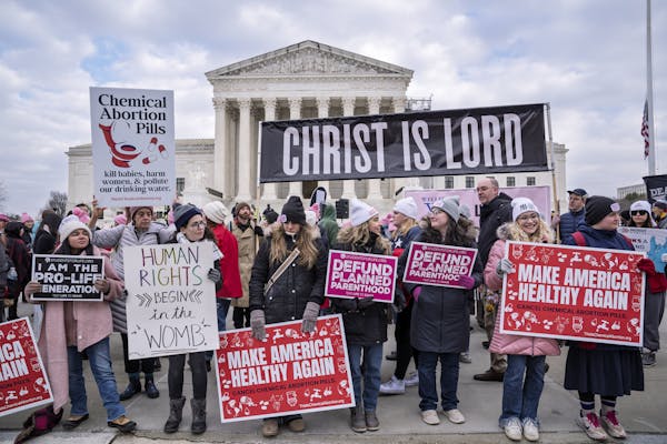 A crowd of women in coats hold signs, one of which reads 'Christ is Lord.'