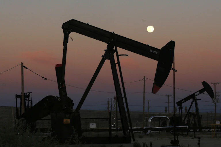 An oil derrick pumps oil in a field at dusk