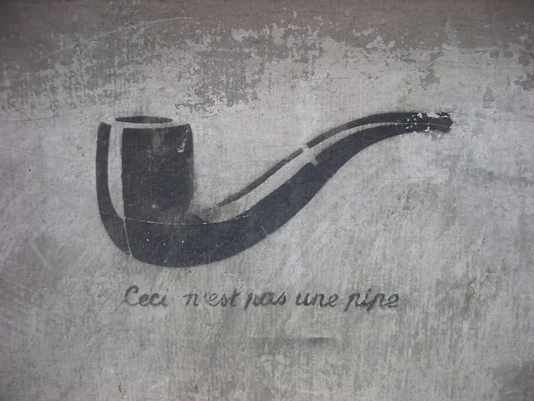 a stencilled pipe spraypainted onto a concrete wall with the words ceci n'est pas une pipe underneath it