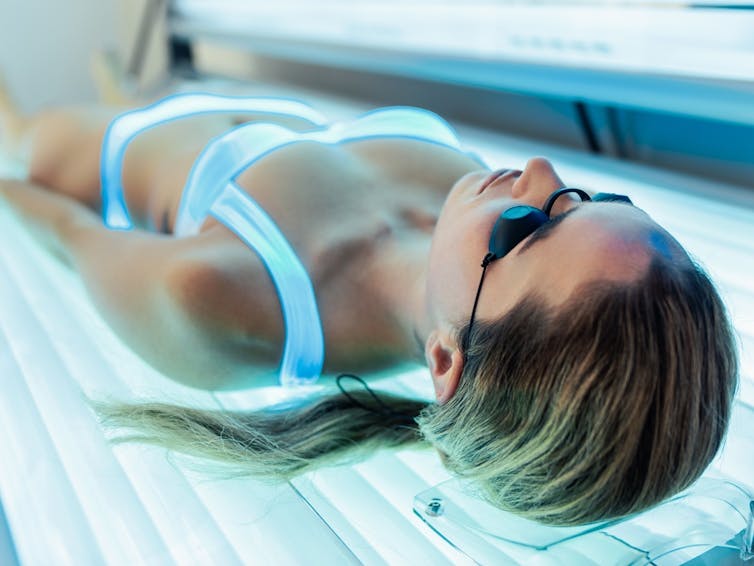 Woman lying on a tanning bed.