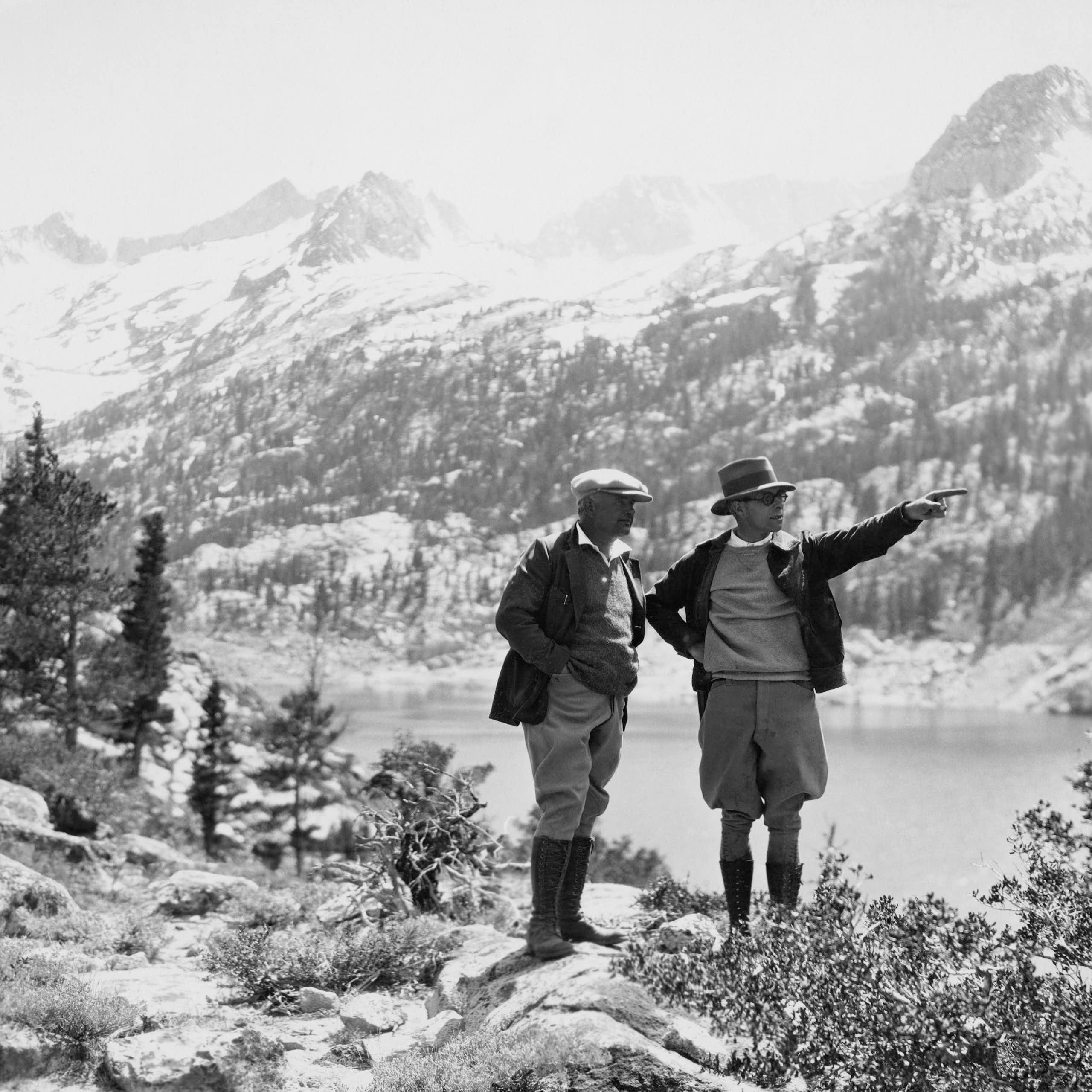 Une photo en noir et blanc de deux promeneurs dans la première moitié du XXe siècle en randonnée dans les montagnes.