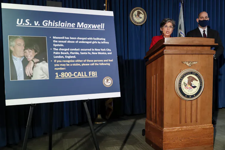 Officials at a podium next to a large photograph displayed on an easel of a man and a woman.