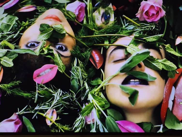 Two women lying with flowers and greenery all over their faces.