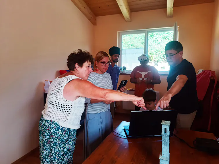 A group of people standing around a computer.