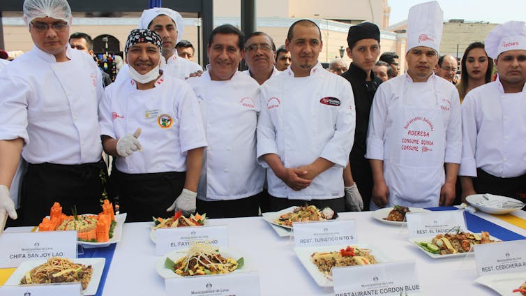 Peruvian chefs stand behind a table displaying their dishes.