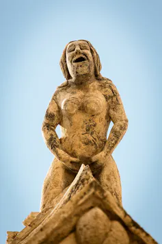 Una estatua de piedra de una mujer tocándose.