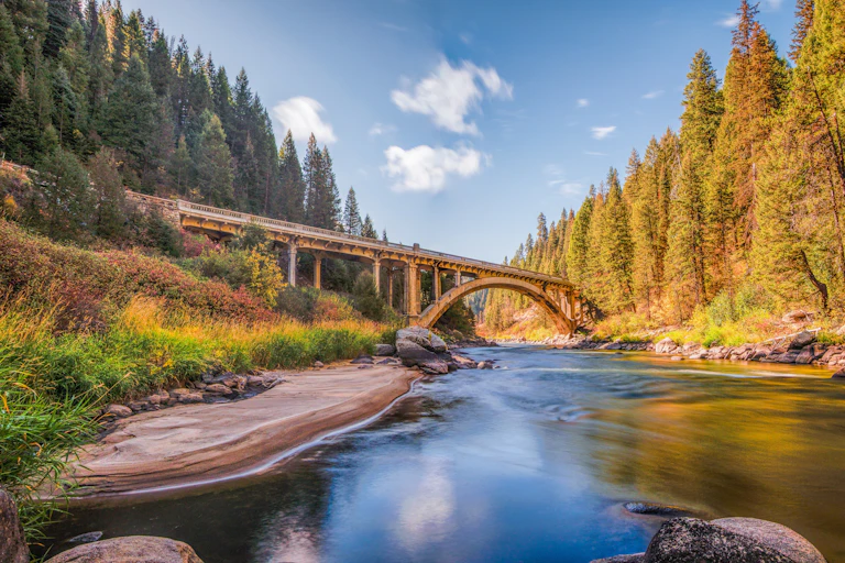 A bridge crosses over a river with forested banks.