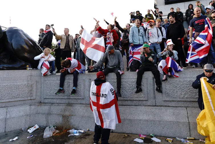 people climbing on a wall wearing flags.