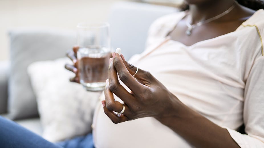 Pregnant woman holding a pill and glass of water