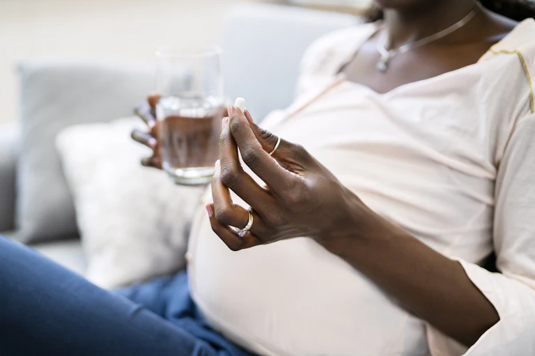 Pregnant woman holding a pill and glass of water