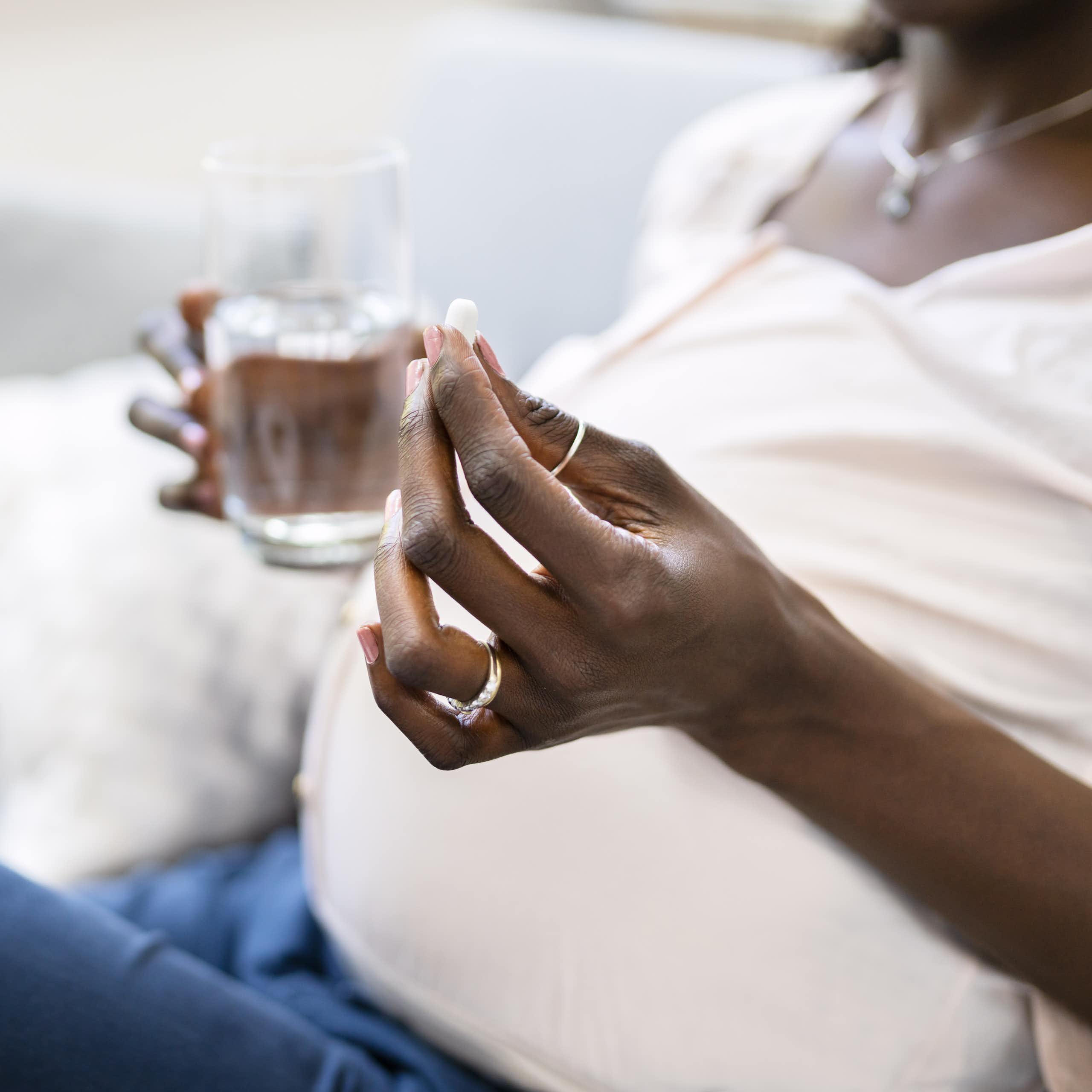 Pregnant woman holding a pill and glass of water