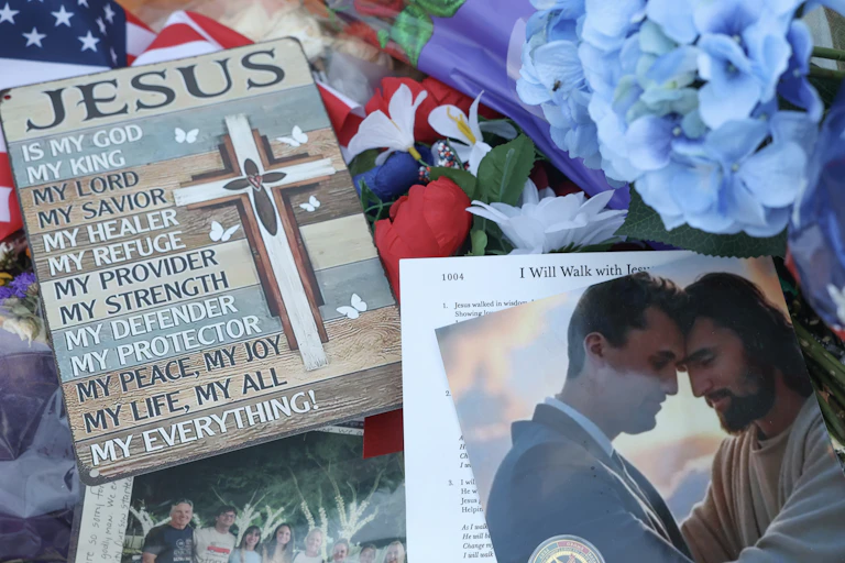 A collection of flowers, American flags and an image of a young man touching foreheads with Jesus Christ.