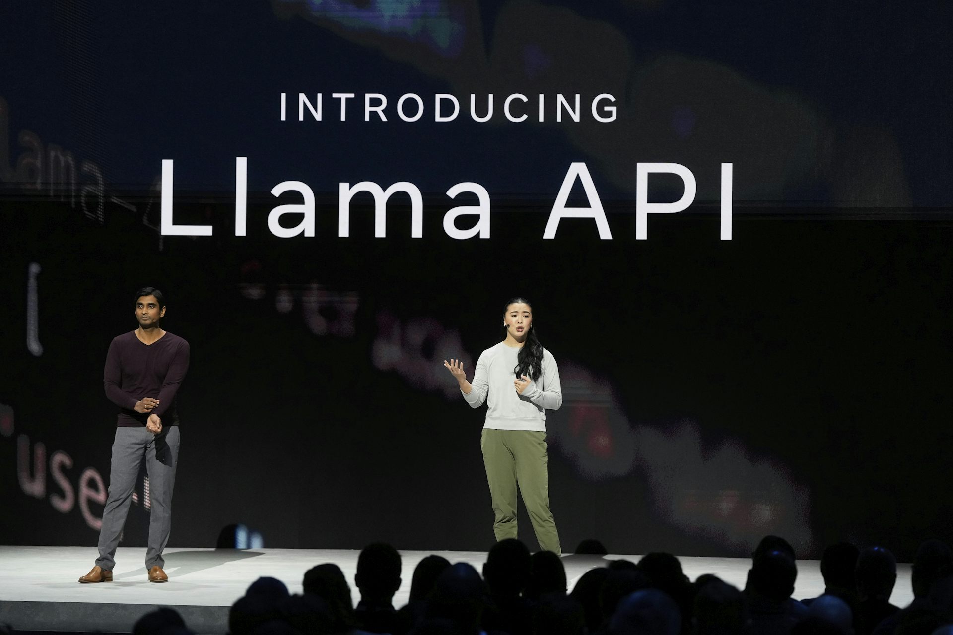 Two people stand on stage in front of a screen that says 'introducing Llama API'