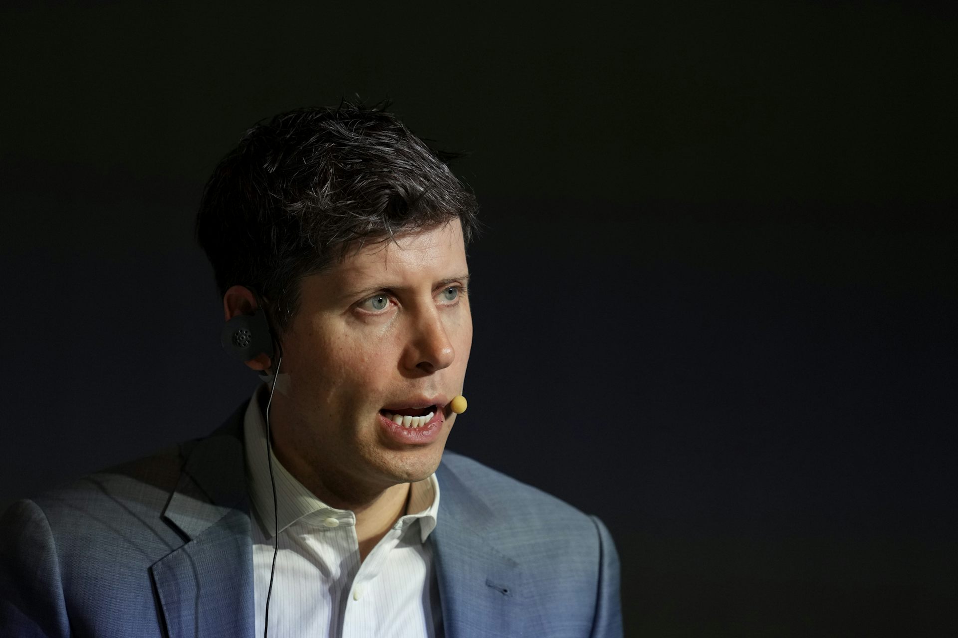 A white man speaks while wearing a headset with a microphone