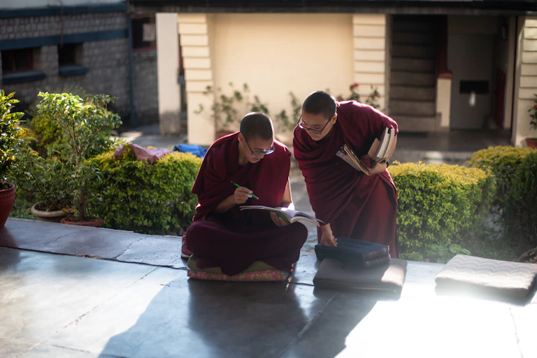 Two woman in religious attire study a book.