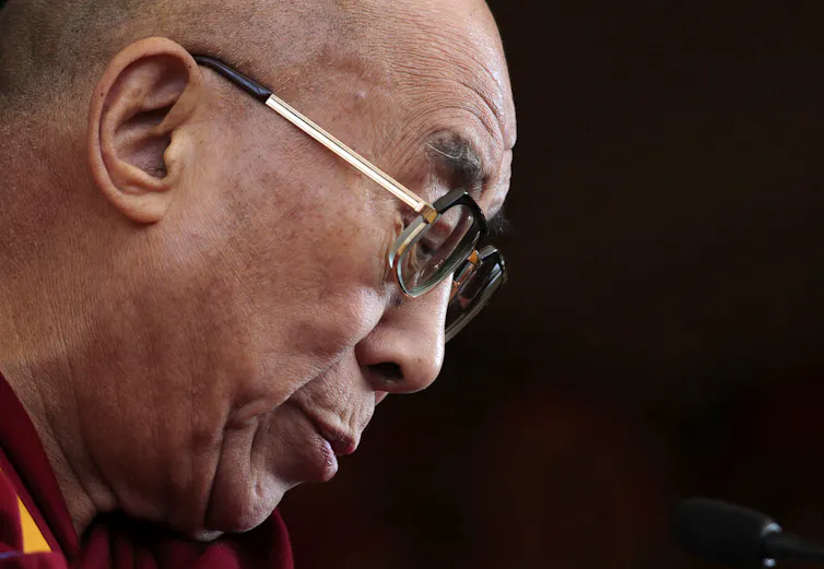 A man with glasses looks down.