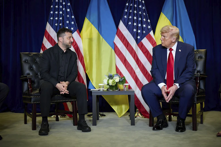 US president, Donald Trump, sits with Ukrainian president, Volodymyr Zelenskyt, with their naitonal flags behind them.