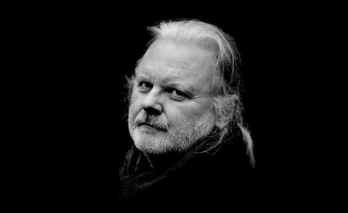 Retrato en blanco y negro de un hombre de barba y pelo blanco.