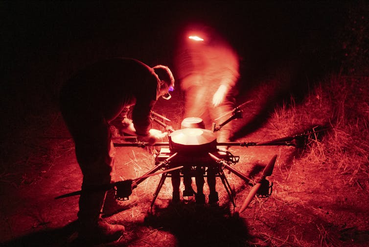 Ukrainian servicemen setting up a drone at night.