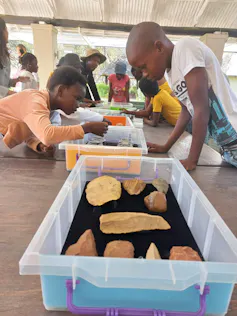 Children leaning over a table with boxes of items