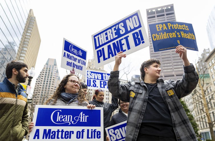 People hold signs saying 'There's no Planet B,' 'Save the U.S. EPA' and other messages.