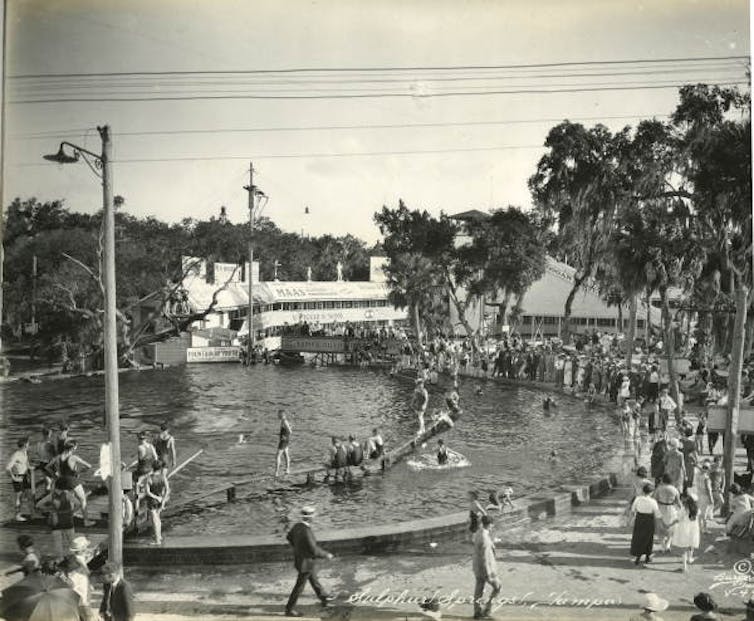 Black-and-white photo of a springs pool with lots of swimmers in and around it.