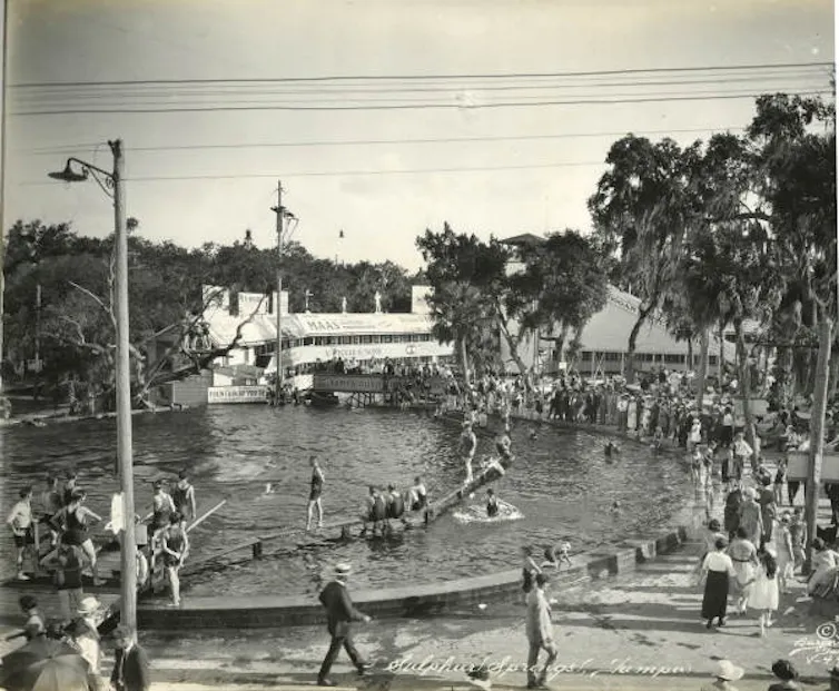 Black-and-white photo of a springs pool with lots of swimmers in and around it.