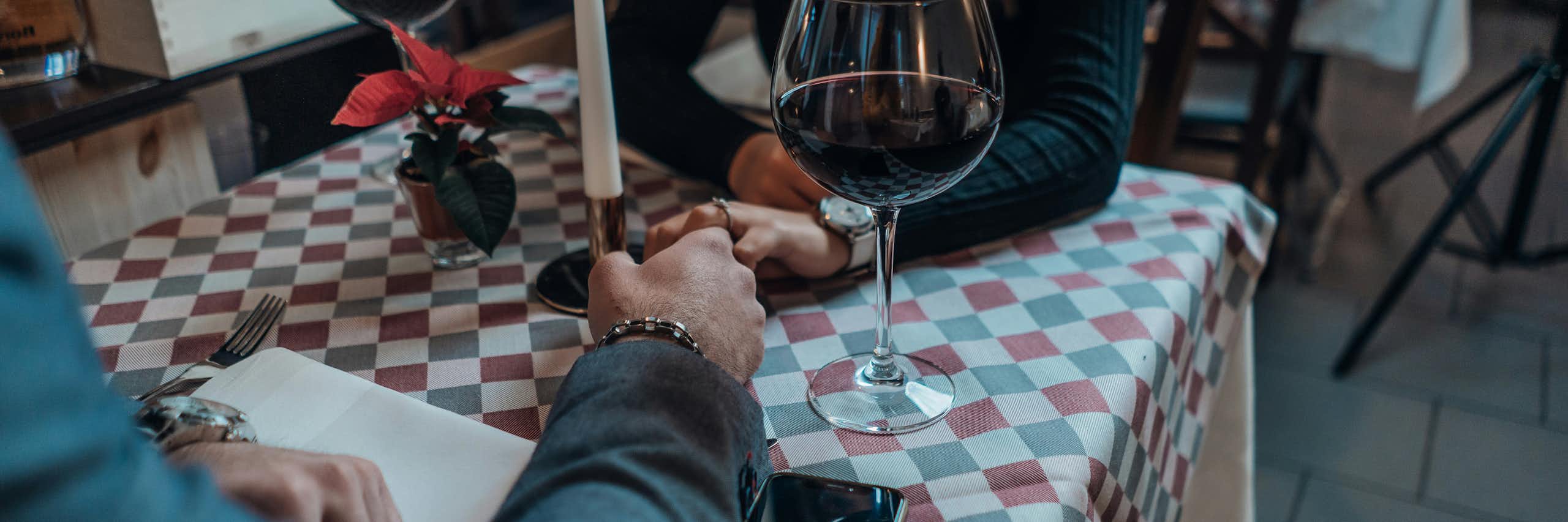 Deux personnes se tiennent la main sur une petite table dans un restaurant.