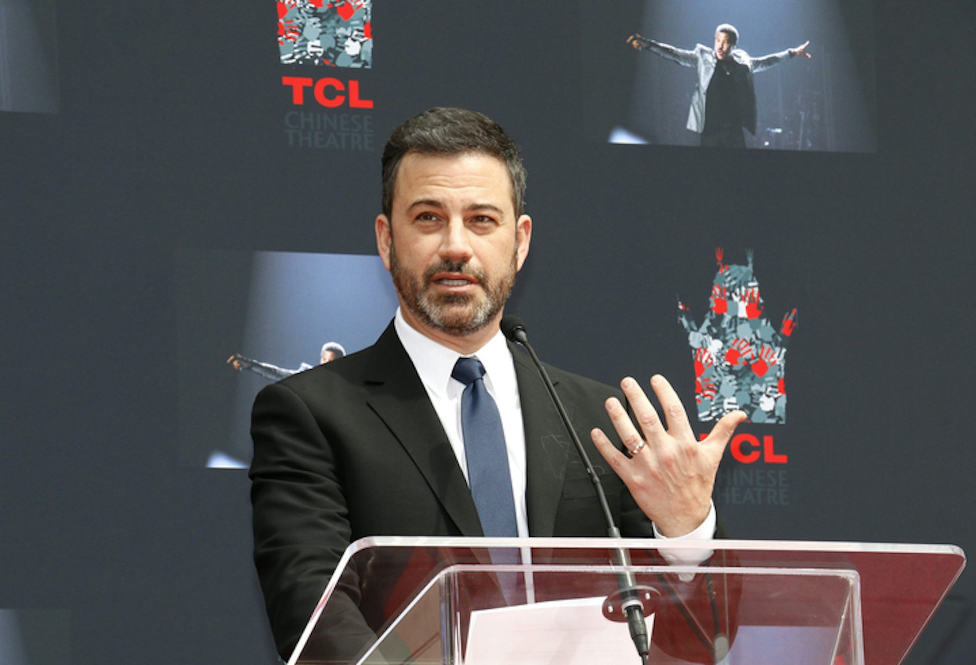 US comedian Jimmy Kimmel gestures with his hand while standing at a podium.